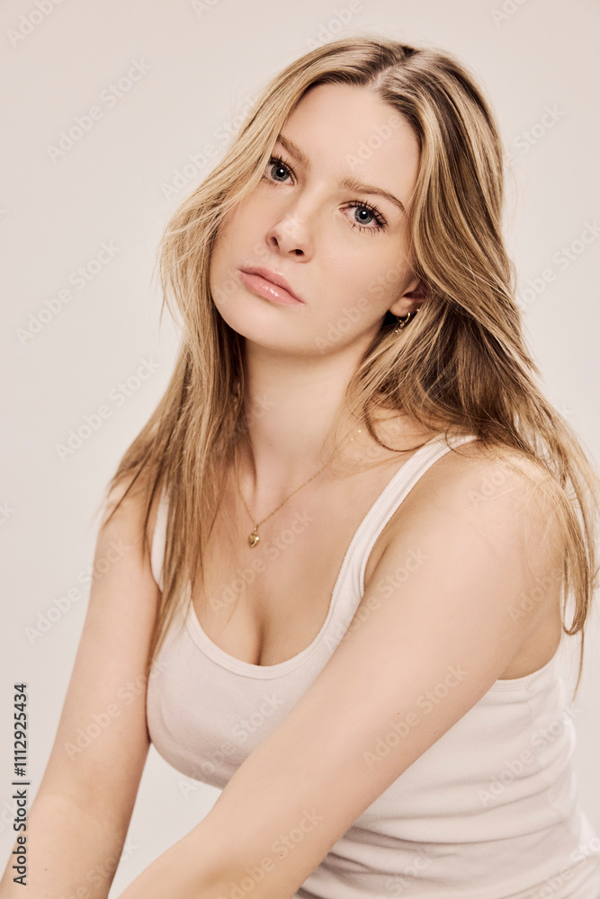 Portrait of young beautiful woman sitting on a stool in a studio setting. Portrait of young beautiful woman sitting on a stool in a studio setting.