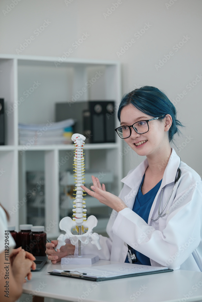 A woman in a white lab coat is holding a model of the spine A woman in a white lab coat is holding a model of the spine