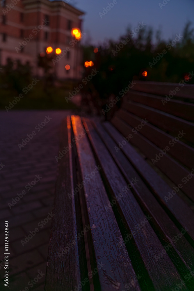 Evening park bench with glowing streetlights and residential buildings Evening park bench with glowing streetlights and residential buildings