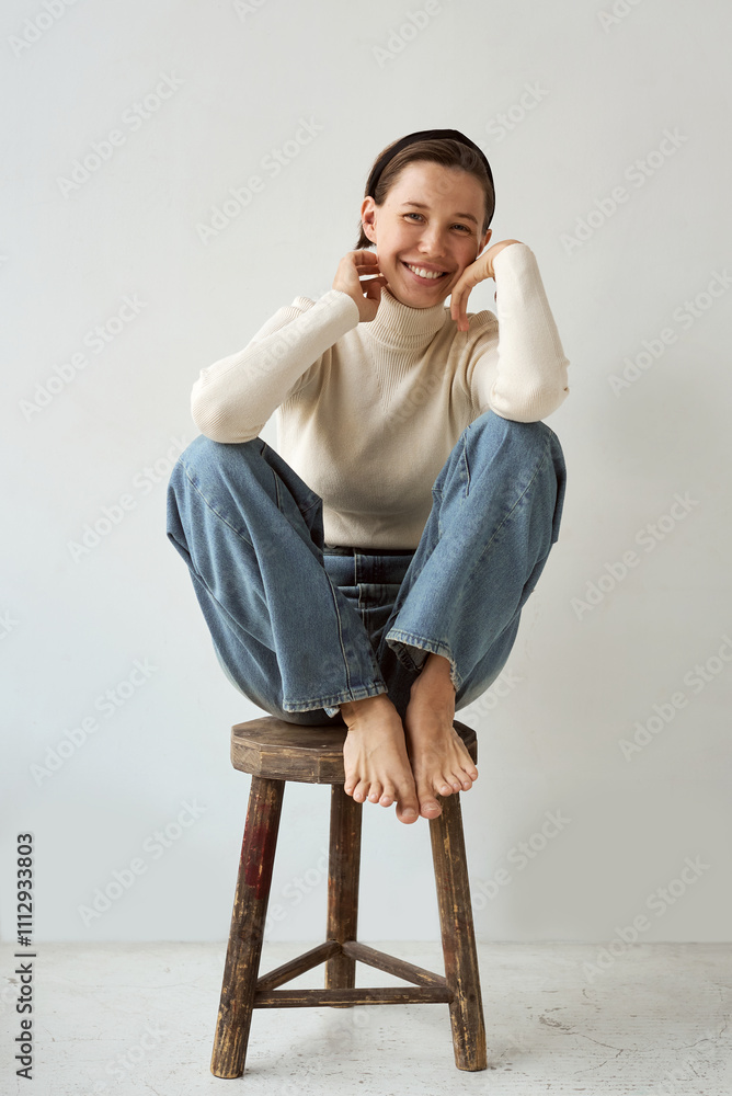 Cheerful young woman sitting on a stool Cheerful young woman sitting on a stool