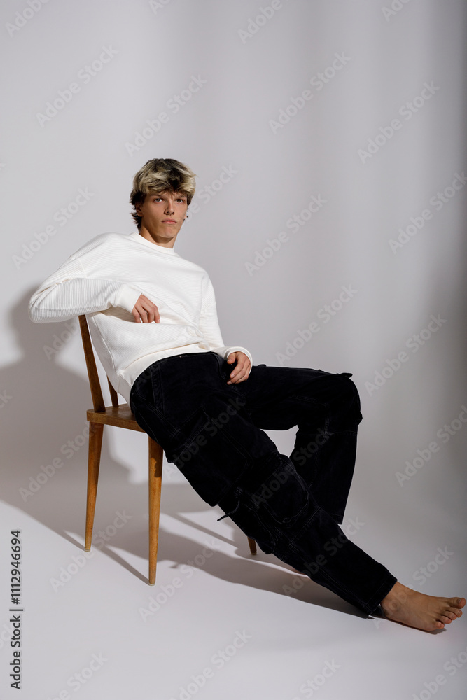 A young man in a white sweater and black pants A young man in a white sweater and black pants