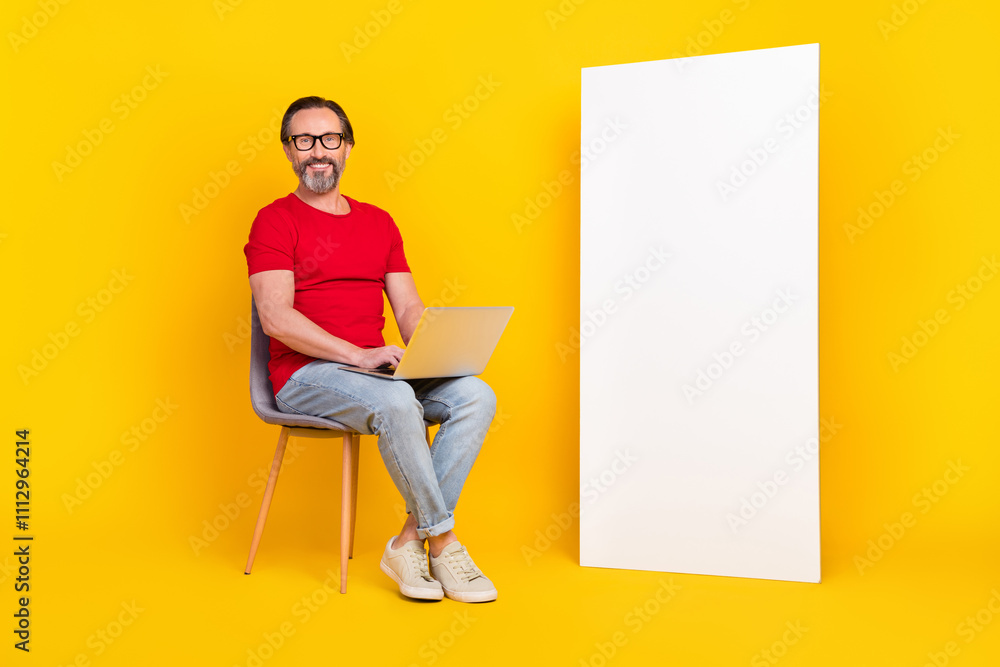 Photo of cute cheerful guy pensioner dressed red t-shirt glasses writing gadget empty space isolated yellow color background Photo of cute cheerful guy pensioner dressed red t-shirt glasses writing gadget empty space isolated yellow color background