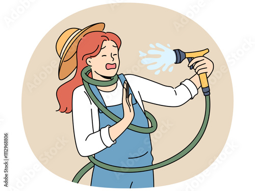 Clumsy woman with garden hose accidentally sprays herself with water while watering backyard lawn during drought. Girl got tangled in garden hose due to failure or lack knowledge of safety precautions