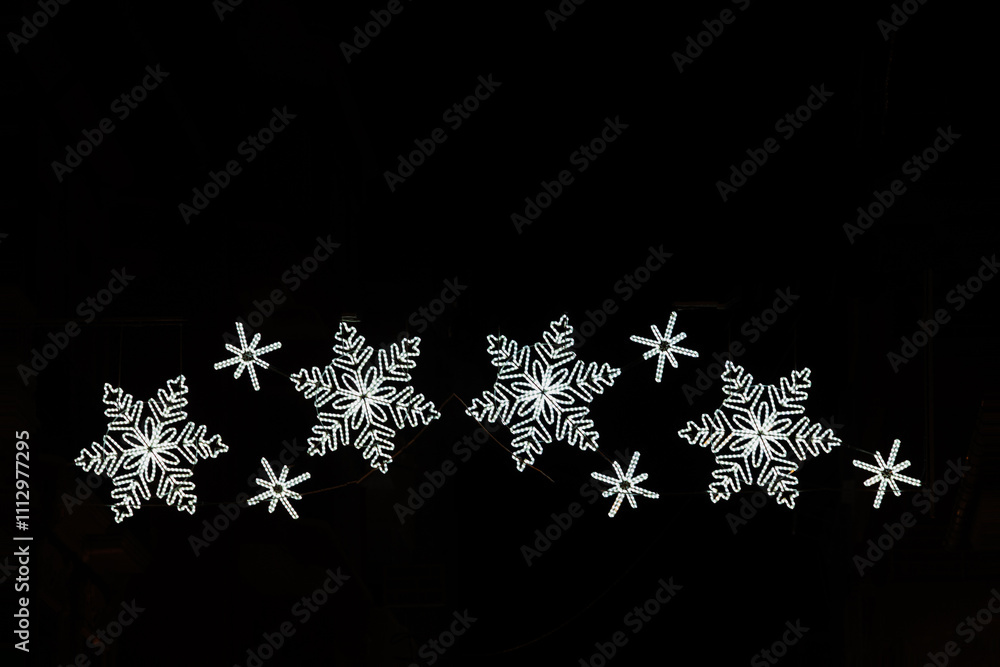 Twinkling christms lights form the shape of four glowing snowflakes Twinkling christms lights form the shape of four glowing snowflakes