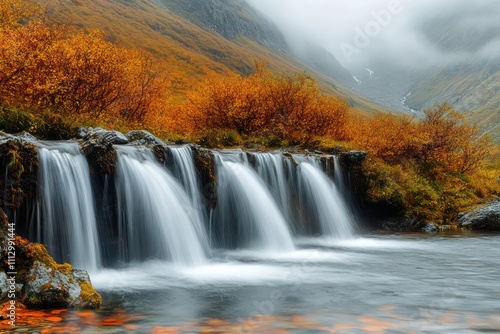 A mountain stream with small waterfalls, surrounded by autumn foliage, viewed from close range at the watera??s edge.
