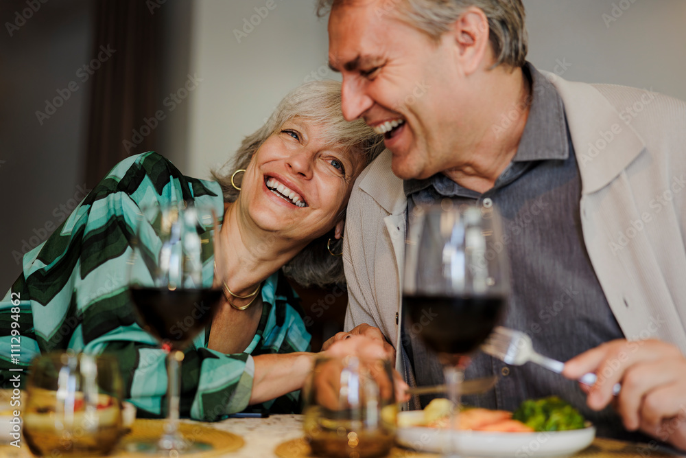 Senior couple laughing and having fun while eating dinner together Senior couple laughing and having fun while eating dinner together