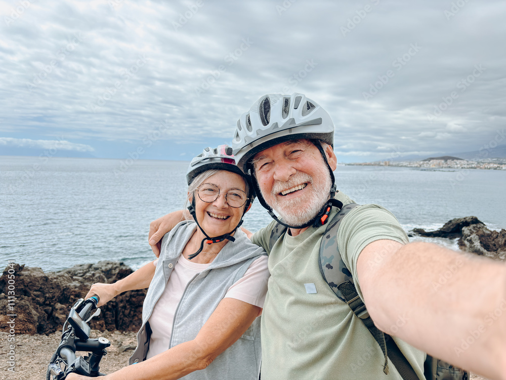 Two happy old mature people enjoying and riding bikes together to be fit and healthy outdoors. Active seniors having fun taking a selfie picture with camera Two happy old mature people enjoying and riding bikes together to be fit and healthy outdoors. Active seniors having fun taking a selfie picture with camera