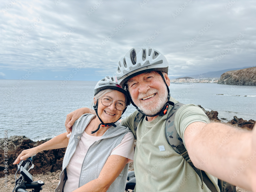 Two happy old mature people enjoying and riding bikes together to be fit and healthy outdoors. Active seniors having fun taking a selfie picture with camera Two happy old mature people enjoying and riding bikes together to be fit and healthy outdoors. Active seniors having fun taking a selfie picture with camera