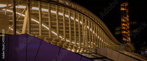 Arching architectural steel and glass structure of Hoog Catharijne central train station and infrastructure hub lit up at night in cityscape photo