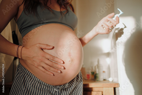 A Pregnant Woman Using Body Lotion in a Bathroom