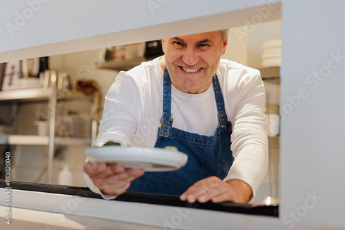 Smiling chef serving food in restaurant kitchen photo