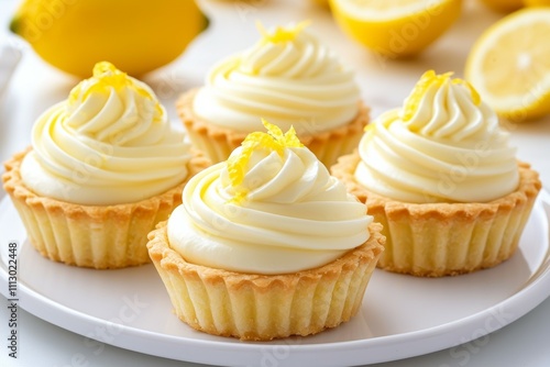 Four lemon cupcakes with whipped cream and lemon zest on top