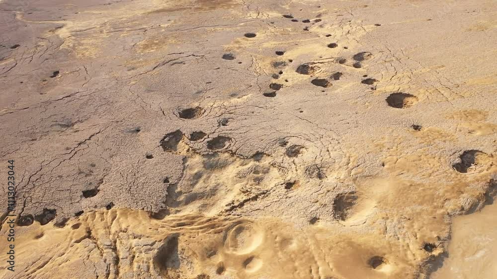 Aerial view of sinkholes near the Dead Sea, Israel. Captured by drone, the dramatic landscape reveals collapsed ground formations caused by the receding shoreline. A striking visual of environmental c Aerial view of sinkholes near the Dead Sea, Israel. Captured by drone, the dramatic landscape reveals collapsed ground formations caused by the receding shoreline. A striking visual of environmental c