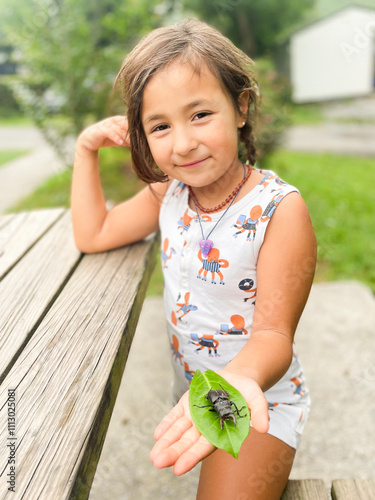 A young girl happily holds a beetle  photo