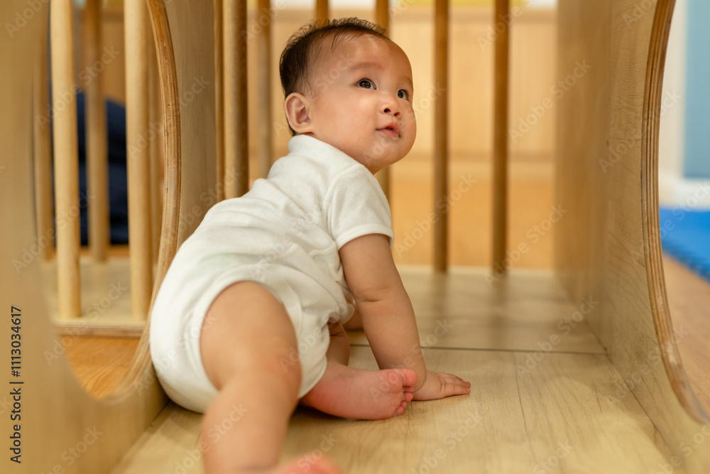 Cute baby exploring by crawling through a wooden play tunnel. Cute baby exploring by crawling through a wooden play tunnel.