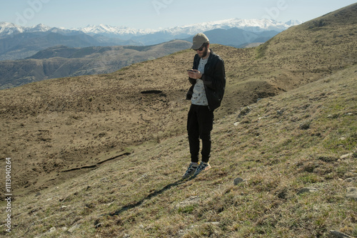 Young man checking his phone in mountains photo