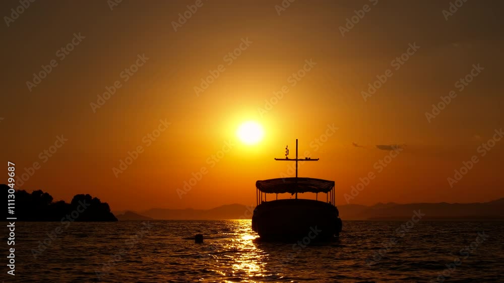 Urban harbor with sailing yacht in nightfall. A view of tropical harbor with moored yacht against orange dusk sky. Urban harbor with sailing yacht in nightfall. A view of tropical harbor with moored yacht against orange dusk sky.