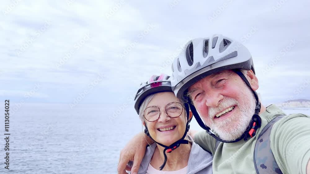 Two happy old mature people enjoying and riding bikes together to be fit and healthy outdoors. Active seniors having fun taking a selfie picture with camera Two happy old mature people enjoying and riding bikes together to be fit and healthy outdoors. Active seniors having fun taking a selfie picture with camera