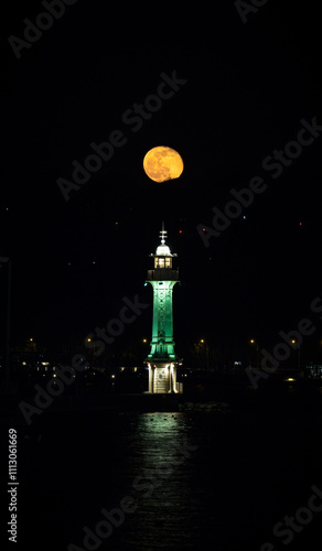 Full moon rising over the Geneva lighthouse at Bains des Paquis photo