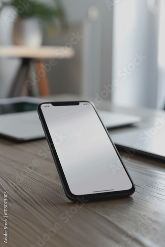 Wallpaper Mural Modern smartphone upright on a wooden desk, surrounded by laptops and a plant in the background, showcasing minimalistic design and technology. Torontodigital.ca