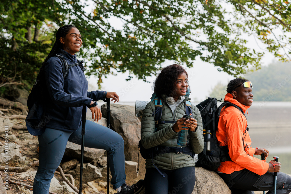 Three hikers taking a break near a lake Three hikers taking a break near a lake