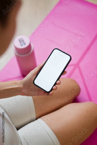 Woman holding smartphone with white screen after yoga session photo