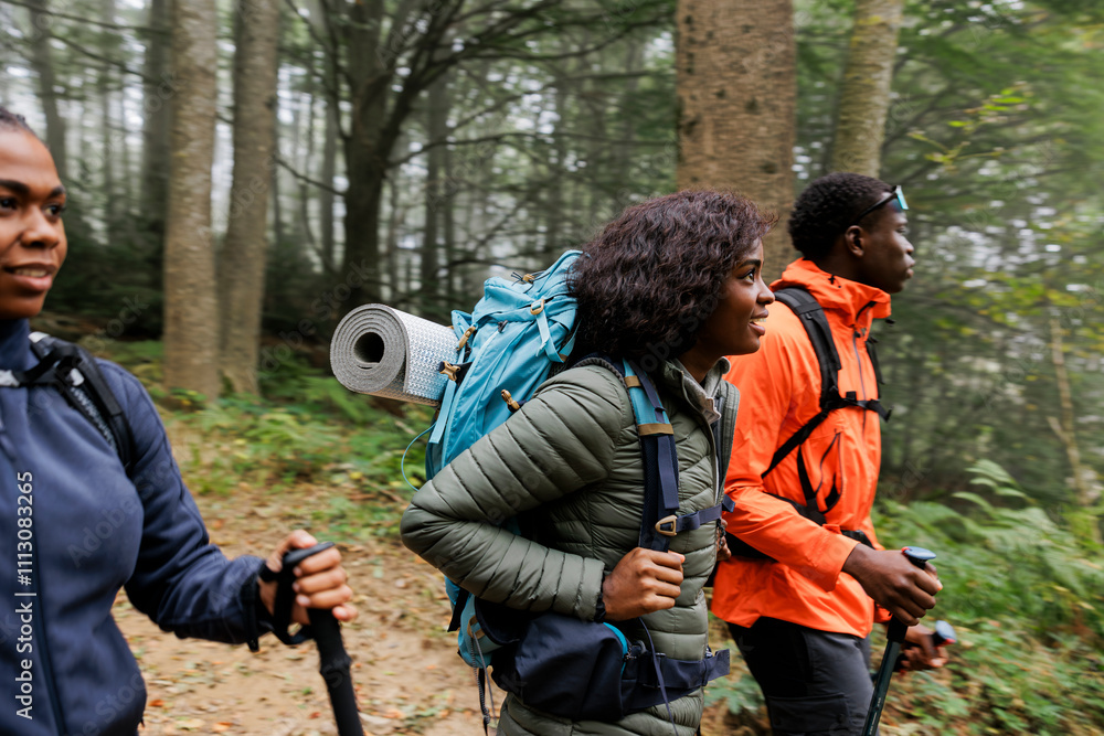 Group of friends hiking through forest wearing backpacks Group of friends hiking through forest wearing backpacks