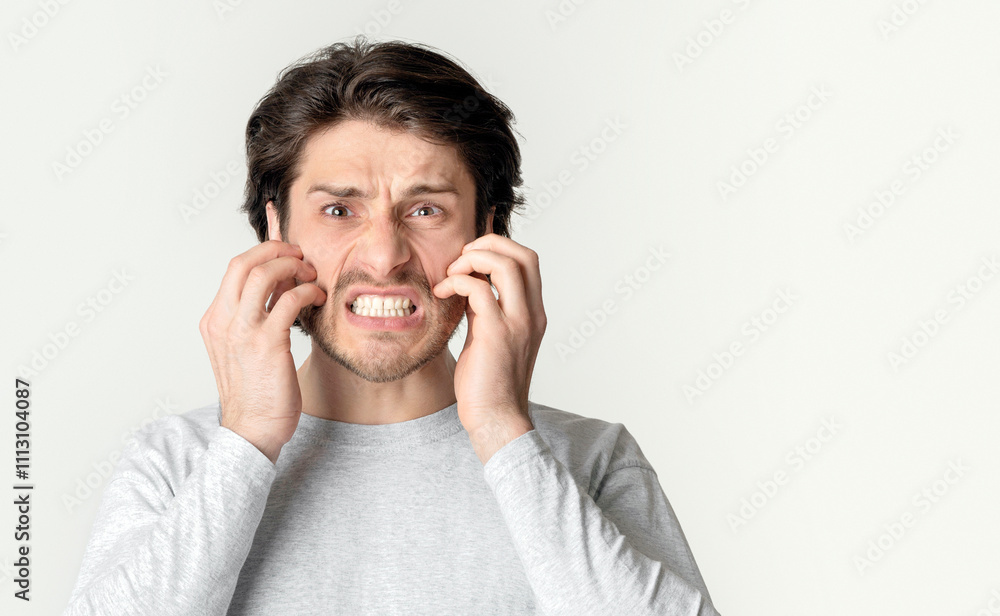 Allergy concept. Millennial man scratches his cheeks. isolated on gray background Allergy concept. Millennial man scratches his cheeks. isolated on gray background