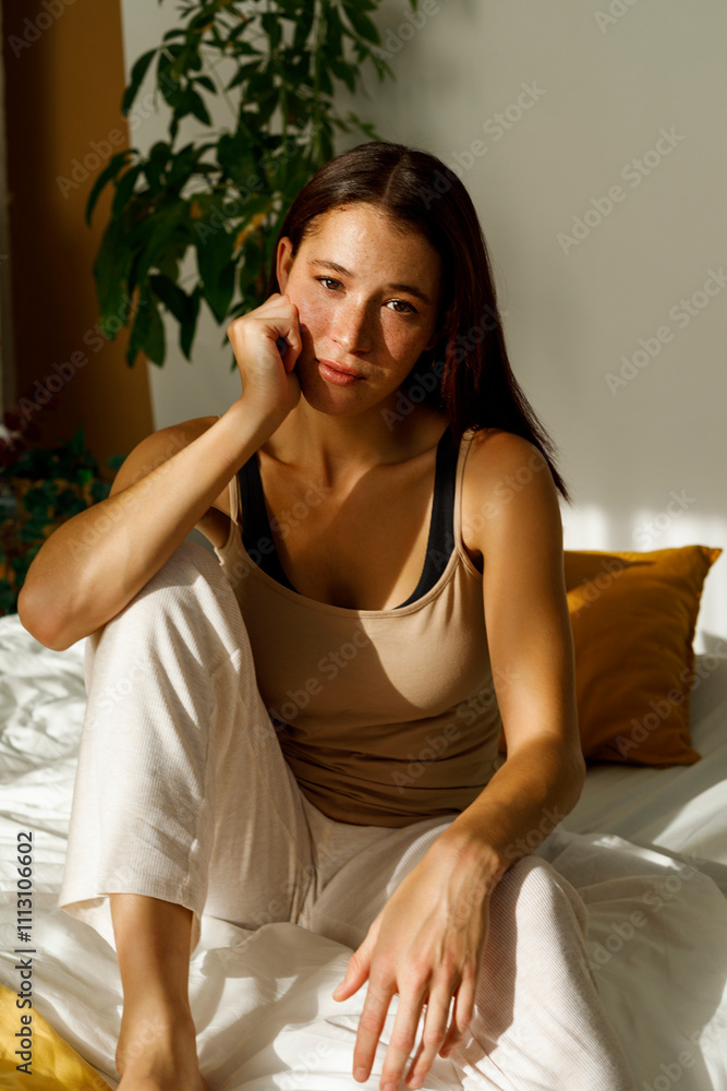 Young woman sitting thoughtfully on a bed Young woman sitting thoughtfully on a bed