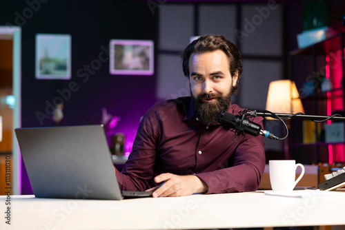 Influencer in home studio recording live broadcast for online streaming platforms, reading messages from fans on laptop. Media star hosting q and a session, answering questions from audience photo