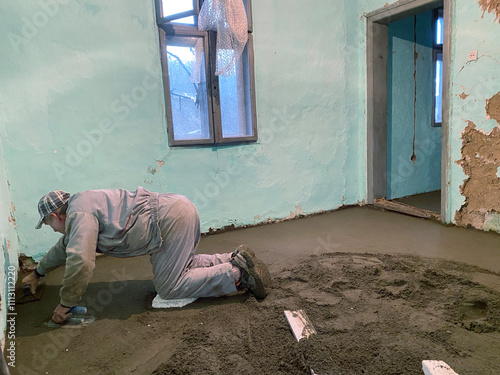 Cement mason tradesmen smoothes out concrete.  photo