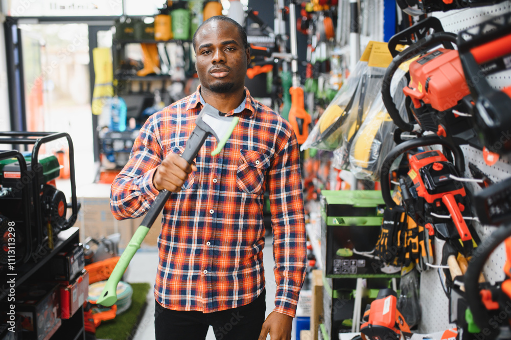 A young african american man chooses axe in the hardware store A young african american man chooses axe in the hardware store