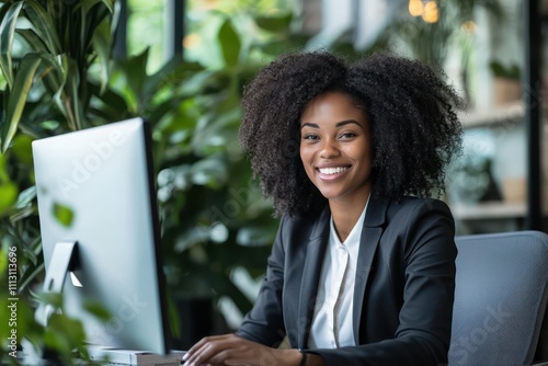 Happy young businesswoman working on a computer in the office. African American executive managing a financial project at her desk