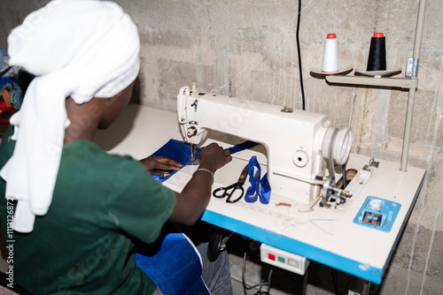 Seamstress sewing blue fabric with white sewing machine photo