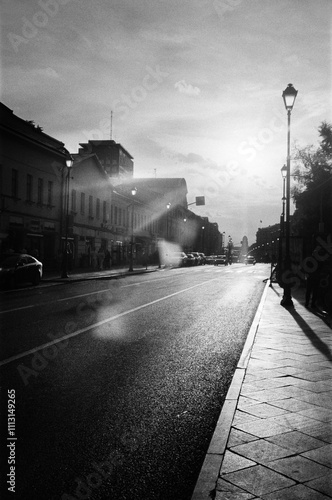 Sunset view along a quiet city street with lampposts and buildings photo