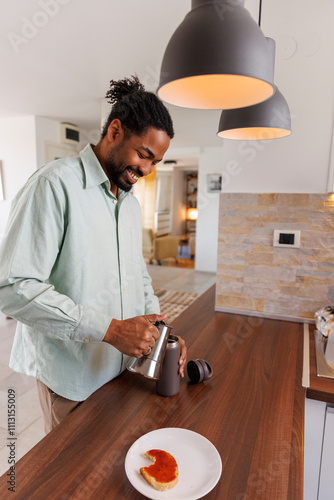 Happy freelancer pouring coffee in insulated bottle photo