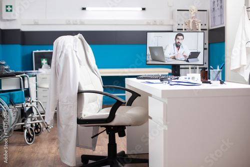 Computer monitor on desk shows doctor conducting videocall consultation in quiet empty office. Desktop pc displays healthcare physician discussing treatment options in virtual medical consultation.