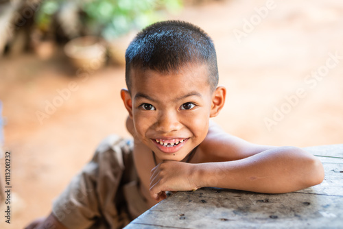 Smiling Rural Thai Boy Leaning on Wooden Table photo