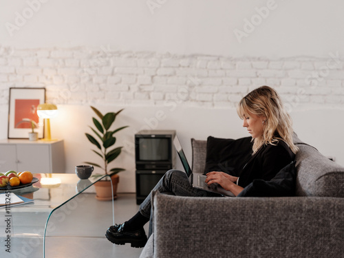 Young Woman Working On Laptop in a Comfortable Lounge Setting photo