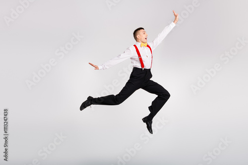 Young dancer in a vintage outfit performs an energetic jump against a white background, showcasing graceful motion and joyful expression