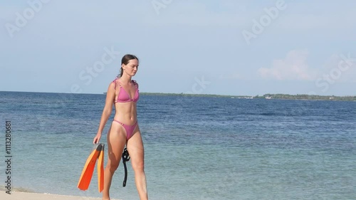 A slender young woman in a swimsuit with fins goes snorkeling. Travel and vacation in Indonesia, vacation in Asia.