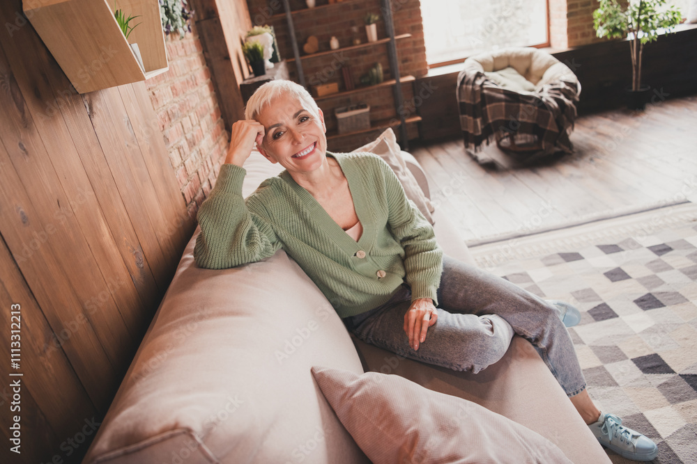 Obraz premium Charming elderly woman enjoying a cozy day at home in trendy sweater