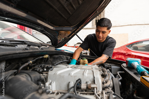 Young latin mechanic fixing a car engine