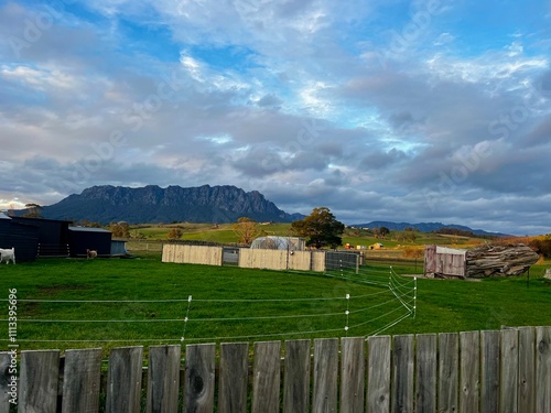 Cradle mountain scenery from farmstay in Tasmania. Green rolling hills shine bright as the golden sun sets.  photo