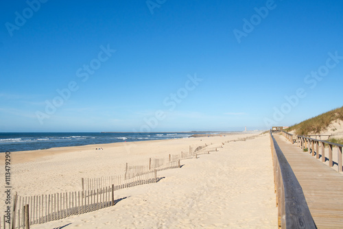 Detail of a light wooden railing made of sticks placed on the white sand of a beach and netx to de sea at Costa Nova in Aveiro, Portugal.