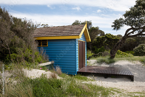 Blue and yellow bathing box surrounded by sand in Blairgowrie, Victoria, Australia photo