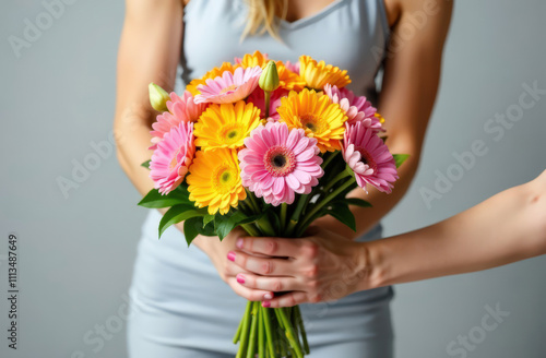 Female holding vibrant gerbera bouquet with outstretched hands on gray background