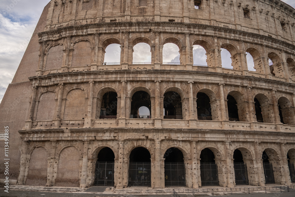 Fototapeta premium Arches archictecture of Colosseum (Colosseo) exterior with clouds and sky. Rome, Italy.
