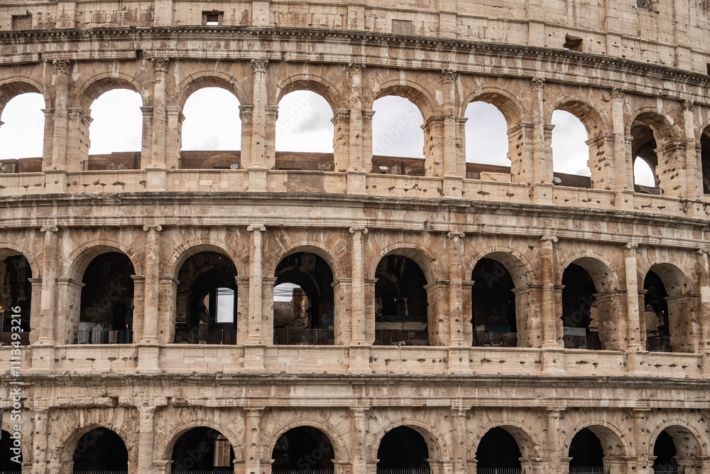 Fototapeta premium Arches archictecture of Colosseum (Colosseo) exterior with clouds and sky. Rome, Italy.