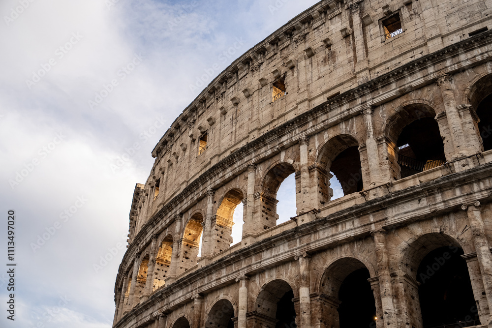 Fototapeta premium Arches archictecture of Colosseum (Colosseo) exterior with clouds and sky. Rome, Italy.